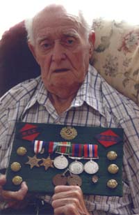 Clarence plus âgé, tenant des médailles, des épinglettes, des insignes d’épaule, etc. datant de ses années à la guerre.