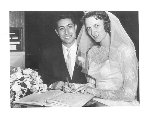 Une mariée et un marié s’assoient à un bureau et signent un livre de mariage.