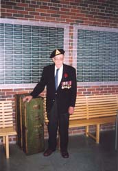 Harold plus âgé, avec des médailles militaires, debout devant le Mur de service au Quai 21.