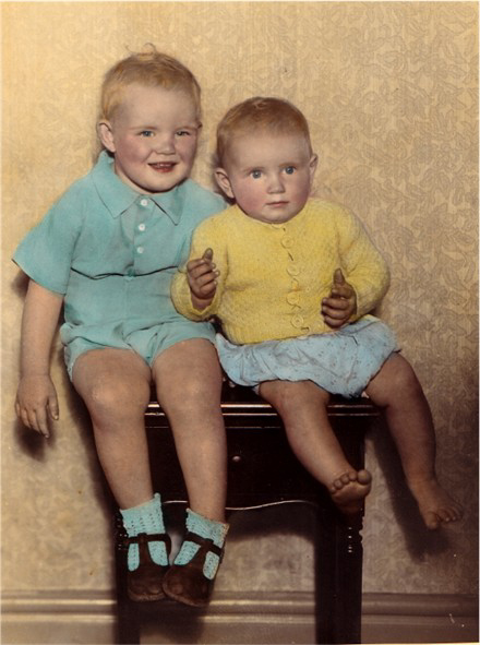 Deux jeunes garçons, assis sur un tabouret.