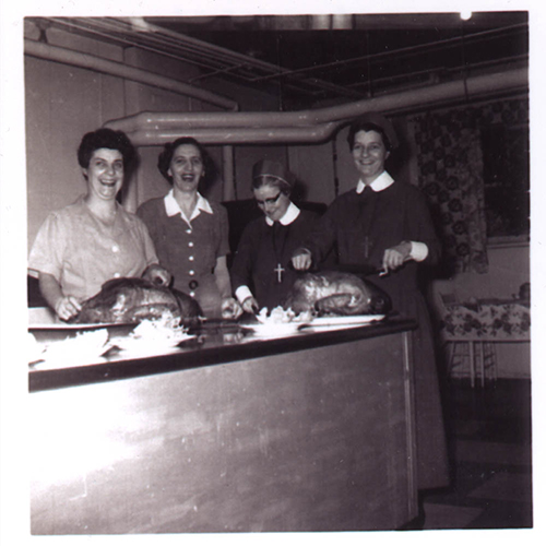 Groupe de quatre dames debout derrière le comptoir de cuisine.