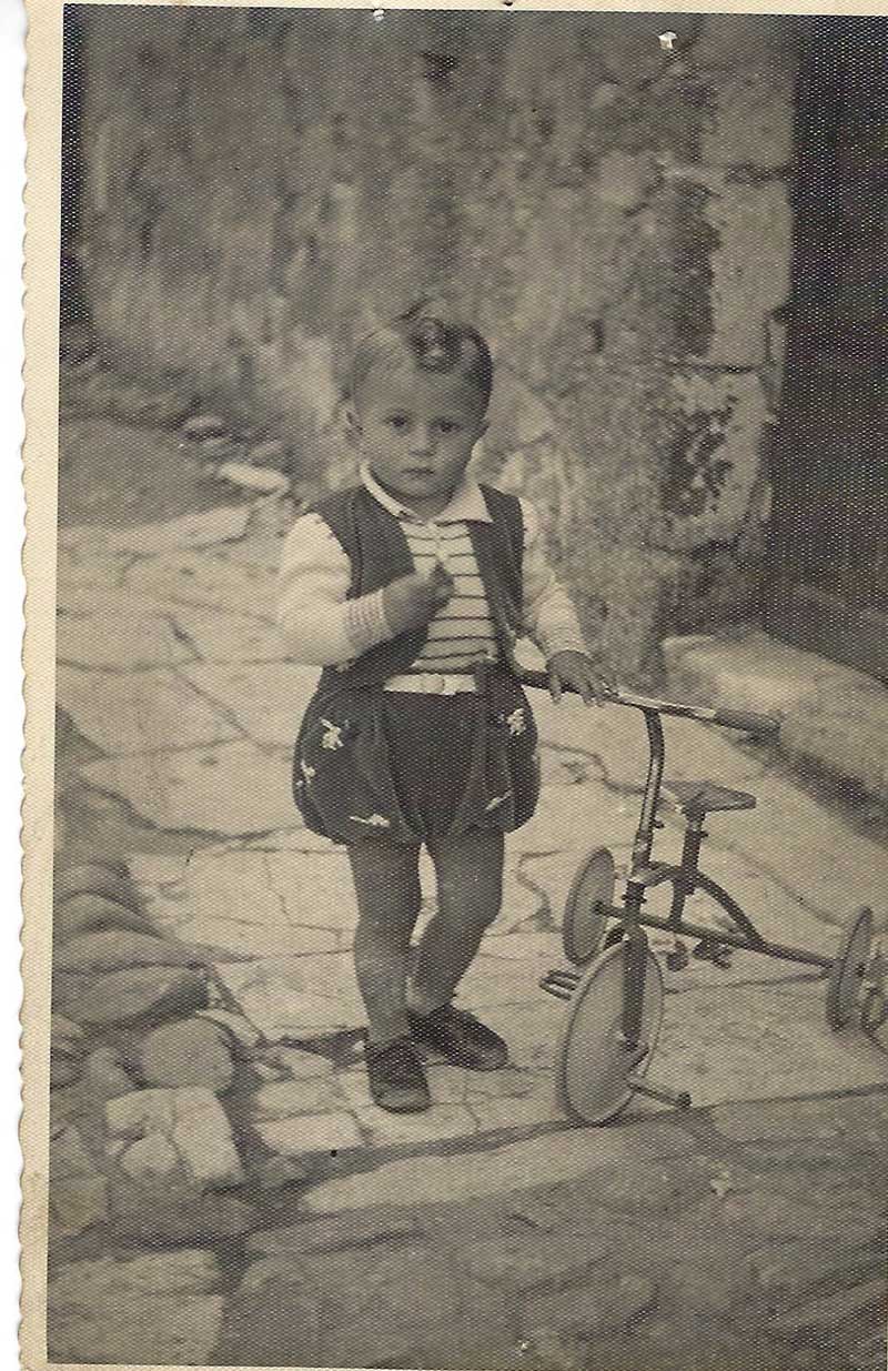 Image en noir et blanc d’un petit garçon portant des vêtements de l’époque.