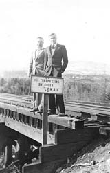 Deux jeunes hommes en costume, debout sur la voie ferrée à côté de signer la lecture Pas d’intrusion par ordre.