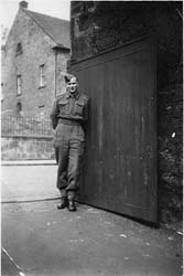 Jeune homme en uniforme debout contre un mur.