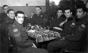 Groupe de jeunes hommes en uniformes militaires, assis autour d’une table.