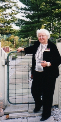 Catherine plus âgée, vêtue de noir et debout contre une barrière.