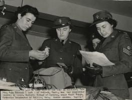 Trois femmes officiers regardant dans un sac de sport et tenant des papiers. 