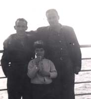 Deux hommes et un petit garçon appuyé contre la balustrade du navire.