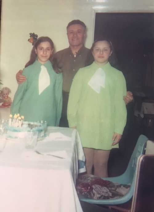 Deux filles en robe vert lime se tiennent de chaque côté de leur père.