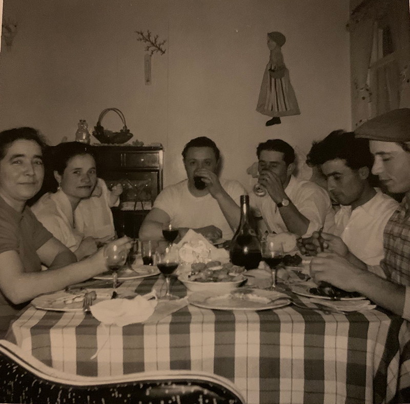 Petit groupe d’hommes et de femmes assis à une table, mangeant et buvant.