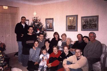 Plusieurs membres de la famille assis autour du divan du salon pendant le temps des fêtes. 