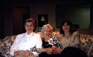 Photographie couleur récente de trois femmes assises sur le divan d’un salon.