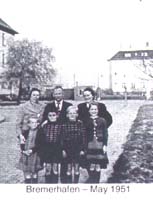 Sept membres de la famille posant sur le trottoir devant un immeuble. 