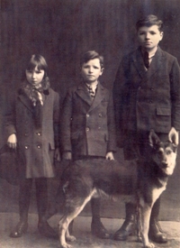 Portrait de trois enfants en vêtements sombres, un chien devant eux.