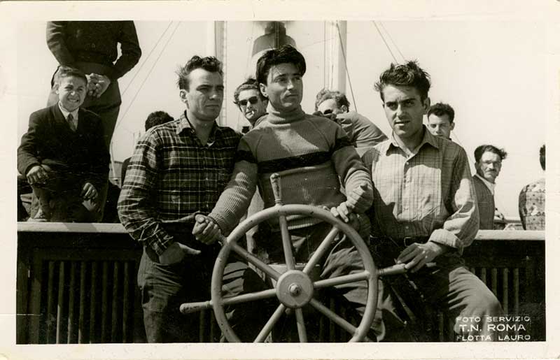 Trois jeunes hommes derrière la barre d’un navire. Ils font semblant de diriger le navire.
