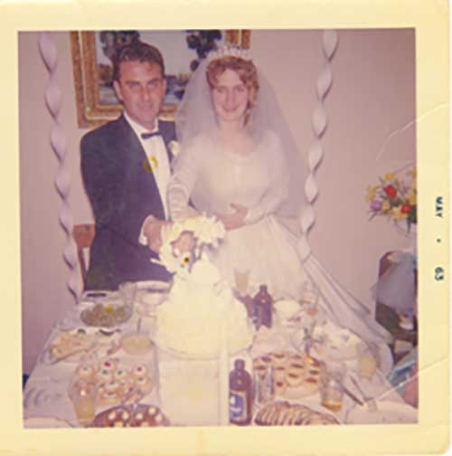 Un couple de mariés devant une table sur laquelle se trouvent une grande quantité de nourriture et un gâteau de mariage.