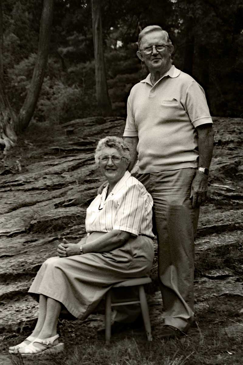 Une photo en plein air avec une femme assise et un homme debout derrière elle.