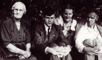 Femme plus âgée avec trois jeunes personnes, leurs mains serrées autour des genoux.