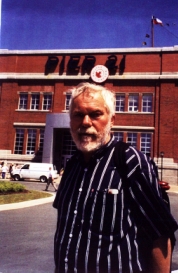 Homme avec des cheveux gris et une barbe, debout à l’extérieur du Musée du Quai 21.