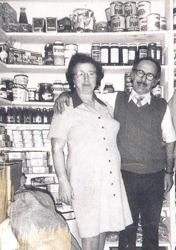 Un homme et une femme se tiennent devant des étagères pleines de nourriture en conserve.