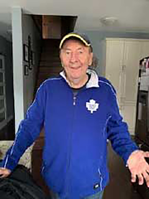 Un homme plus âgé portant une casquette de baseball et une veste bleue des Maple Leafs.