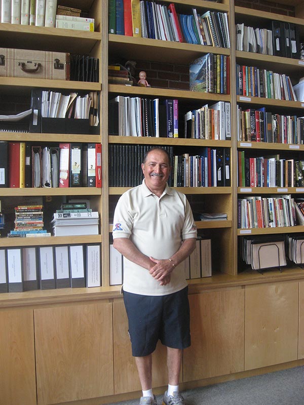 Un Italien souriant devant des étagères de livres.