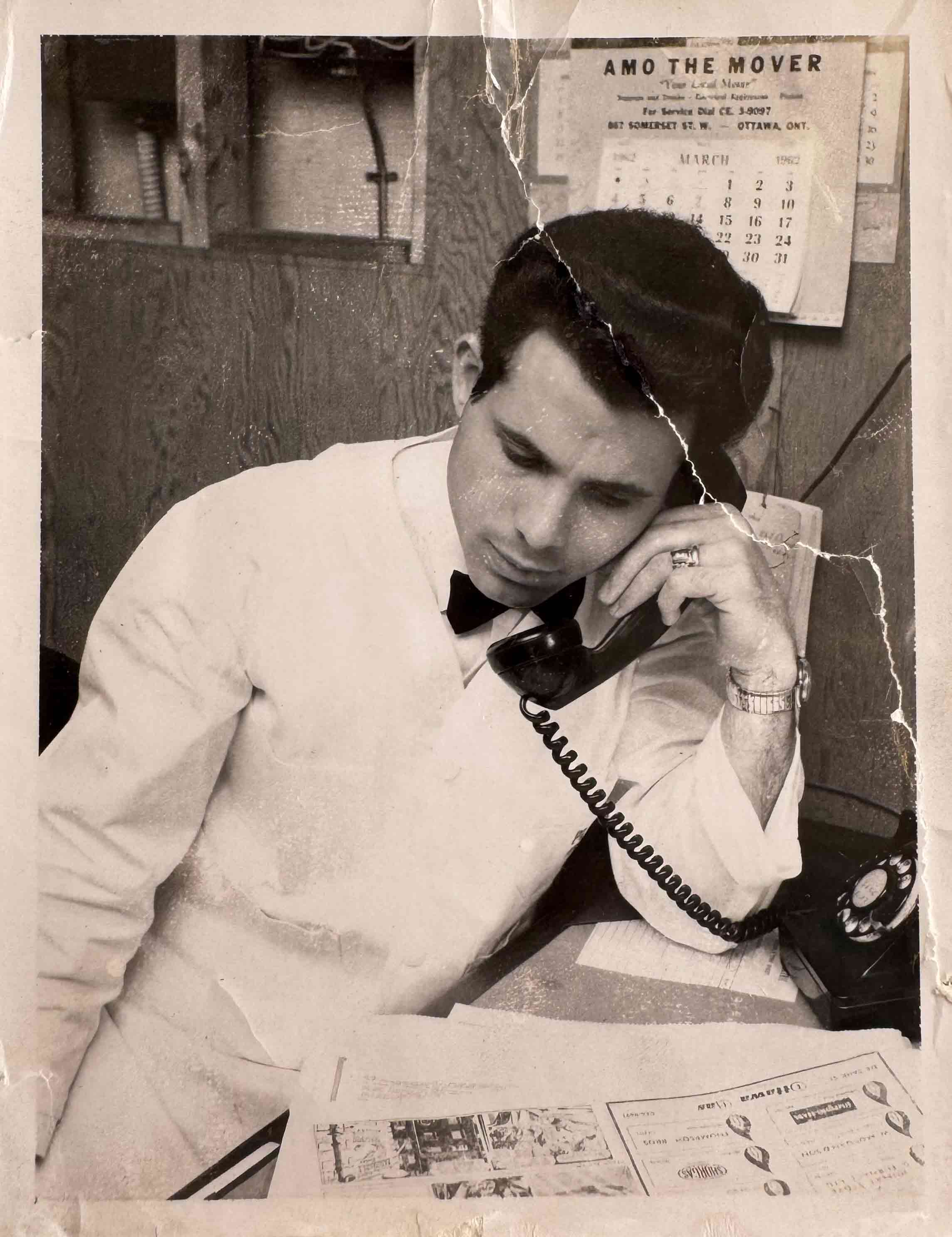 Photographie en noir et blanc d’un homme grec travaillant et parlant au téléphone.
