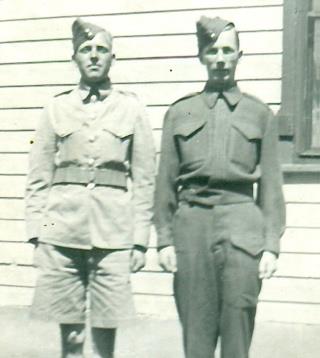 Portrait en noir et blanc de deux hommes blancs en uniforme, debout, les bras le long du corps.