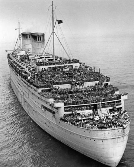 Photo en noir et blanc d’un grand navire sur l’eau, avec des foules de gens sur chaque pont.