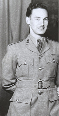 Photo en noir et blanc d’un homme blanc souriant en uniforme.